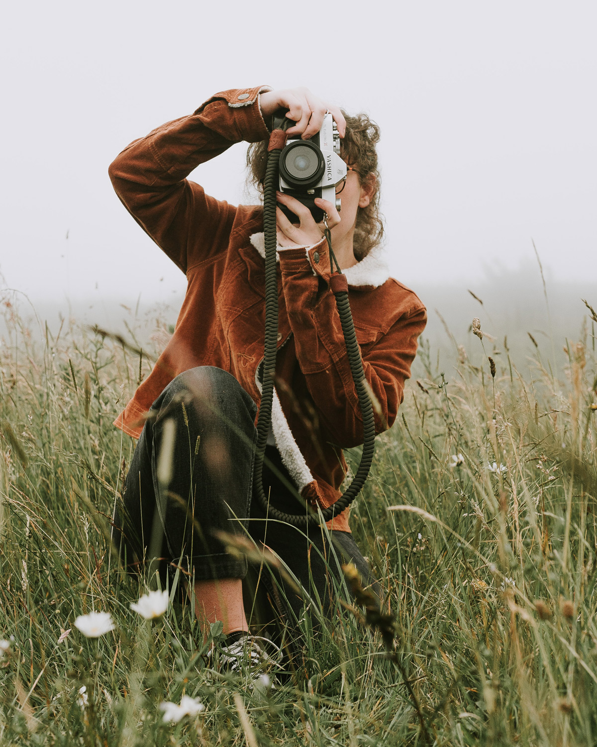 A woman in a field taking a photo with her camera